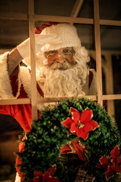 istock happy old Santa Claus using laptop and phone at home 1345293352