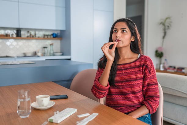 Indian Young Woman Getting Taking A Covid Self Test In The Kitchen Front View Of A Indian Young Woman Taking Rapid Covid Test antigen photos stock pictures, royalty-free photos & images