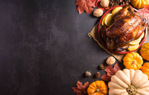 istock Thanksgiving dinner background concept with turkey roasted and all sides dishes, fall leaves, pumpkin and seasonal autumnal decor on dark stone background, top view, copy space. 1345297880