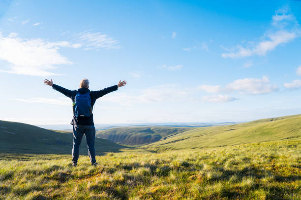 istock Back view man hiker with backpack standing on the mountain with raised hands and enjoying valley view. Travel lifestyle wanderlust adventure. Way to Goal Achievement. Freedom and peace. 1345298105