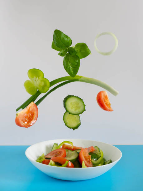 istock Fresh vegetables fly into the salad on a blue-and-white background. Tomato, cucumber.basil, onion. Creative salad. The concept of healthy food, vegan. 1345298140