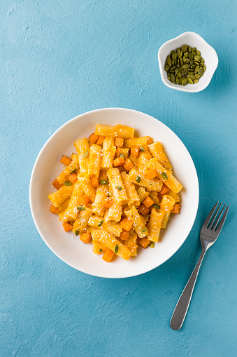 Homemade rigatoni pasta with butternut squash puree sauce and diced butternut squash and coconut cream, pumpkin seeds.