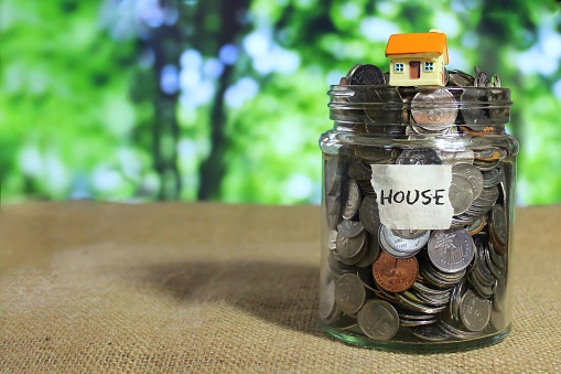 Selective focus image of mini house on top of coins in glass jar