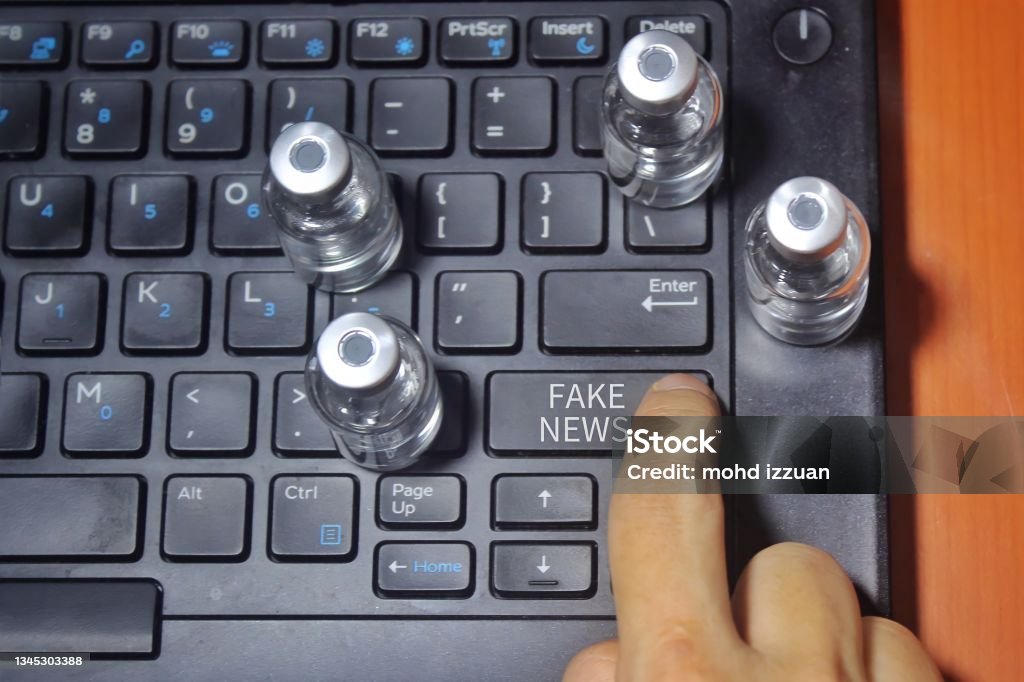 Finger pressing key labeled with text FAKE NEWS Finger pressing key labeled with text FAKE NEWS and surrounded by glass vial Misinformation Stock Photo