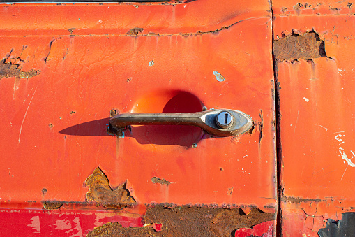Old car door handle. Close-up photo of rusty red car door handle.