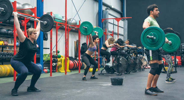 люди, практикующие тяжелую атлетику, поднимают тяжести в тренажерном зале - crosstraining стоковые фото и изображения