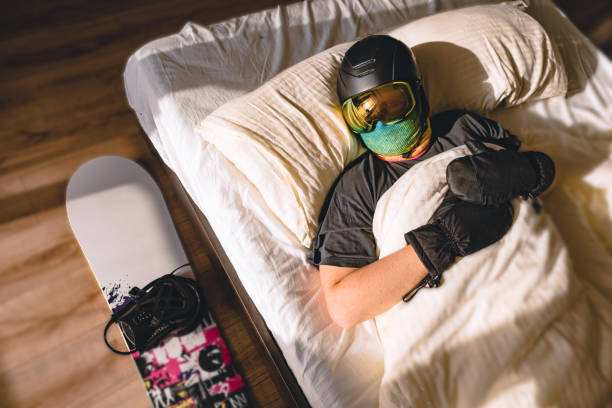 mężczyzna w sprzęcie narciarskim śpi w łóżku ze snowboardem - skiing snow snowboarding winter sport zdjęcia i obrazy z banku zdjęć