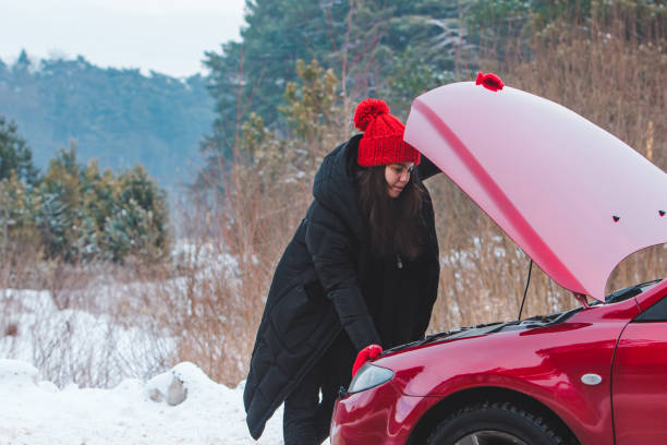 istock woman looking at engine broken car at winter road side 1345309530