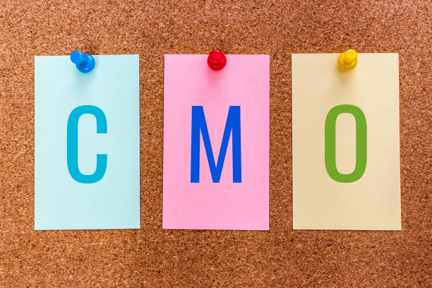 Conceptual 3 letter acronym CMO(chief marketing officer) on multicolored stickers attached to a cork board stock photo