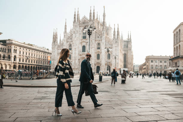 A couple of business people walking in Piazza Duomo in Milano, walking to the office in the morning.