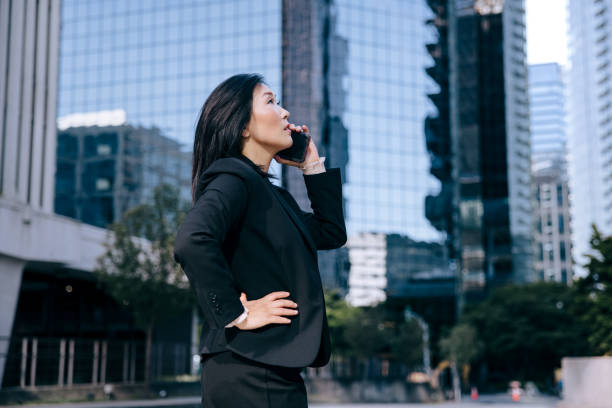istock Korean Business Woman Using Phone In City Setting 1345314865