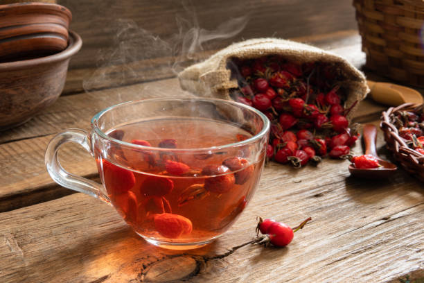 Rosehip tea on wooden background with red fruits A Cup of tea from rosehip useful for health on a wooden background. Dogrose fruit in a canvas bag. wild rose hip stock pictures, royalty-free photos & images