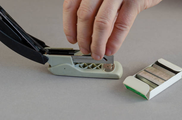 istock Stapler, hand and box of staples on gray background. Man install 1345320700