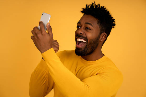 istock Afro man celebrating victory while looking at his mobile phone. 1345324626