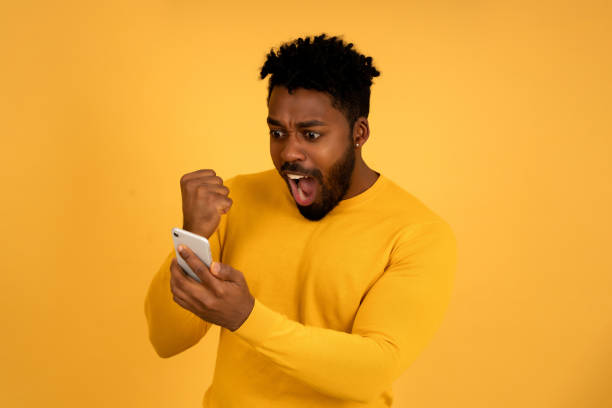 istock Afro man celebrating victory while looking at his mobile phone. 1345324627