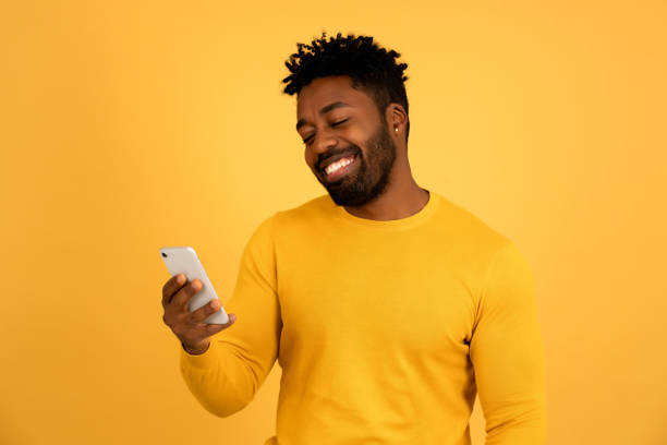 istock Afro man smiling while looking at a mobile phone. 1345324633
