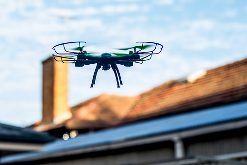 Drone quad copter flying over the roofs. Drone photography and videography. Toy drone. Copy space