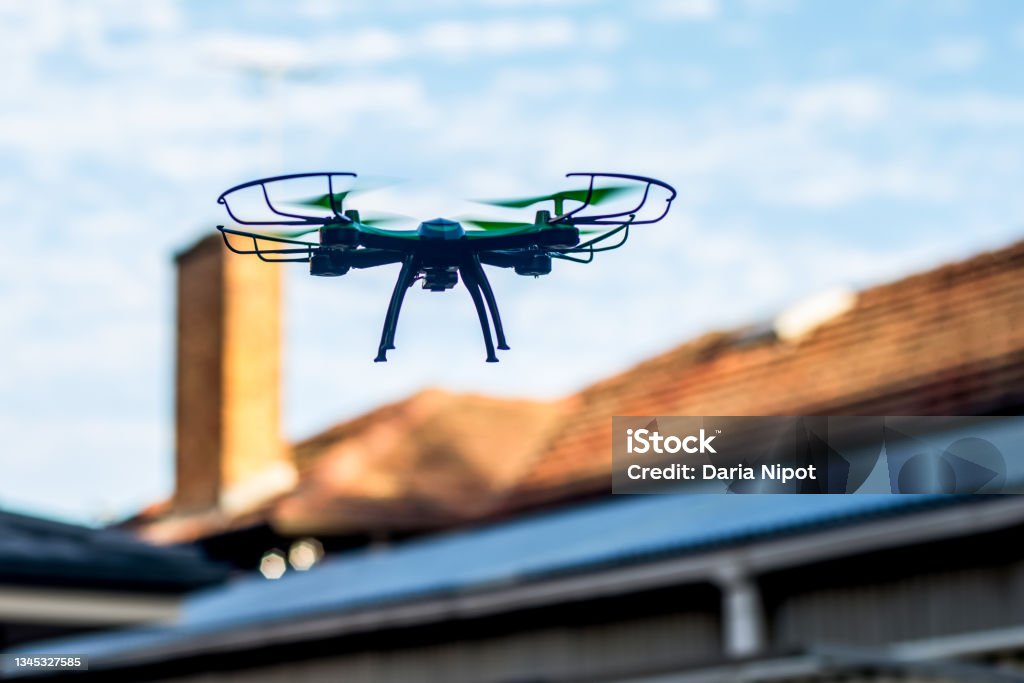 Drone quad copter flying over the roofs. Drone photography and videography. Toy drone. Copy space Drone quad copter flying over the roofs. Drone photography and videography. Toy drone flight. Copy space Drone Stock Photo