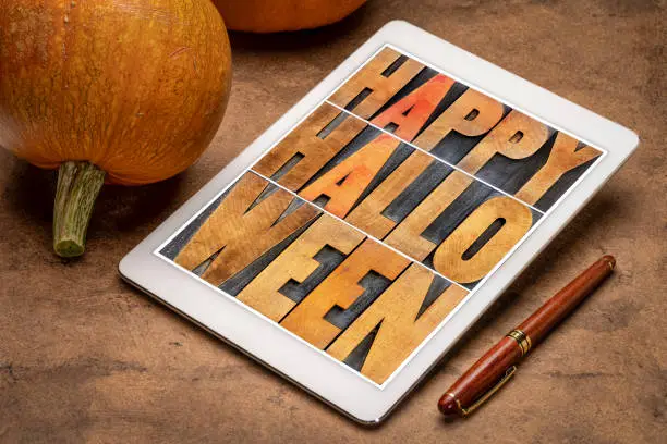 Happy Halloween greeting card -  text in vintage grunge wood type printing blocks on a digital tablet with pumpkins