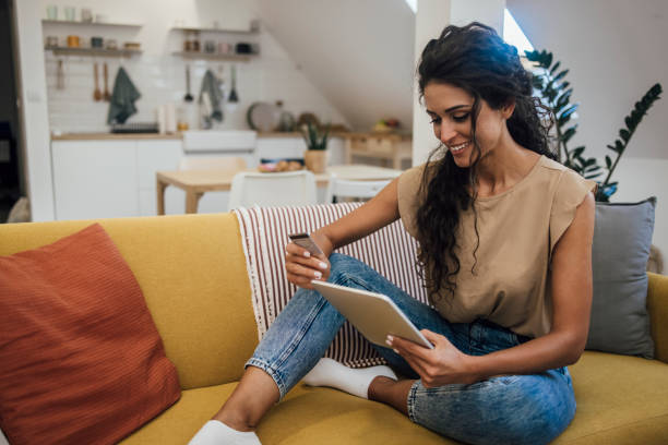 istock Young woman using tablet and shopping online at home 1345331401