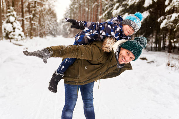 Portrait of father giving piggyback son in winter stock photo