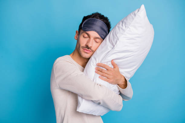 istock Portrait of nice peaceful guy enjoying embracing lying on soft pillow harmony isolated over bright blue color background 1345333825