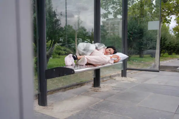 Business Woman sleeping in pyjamas and slippers at bus stop