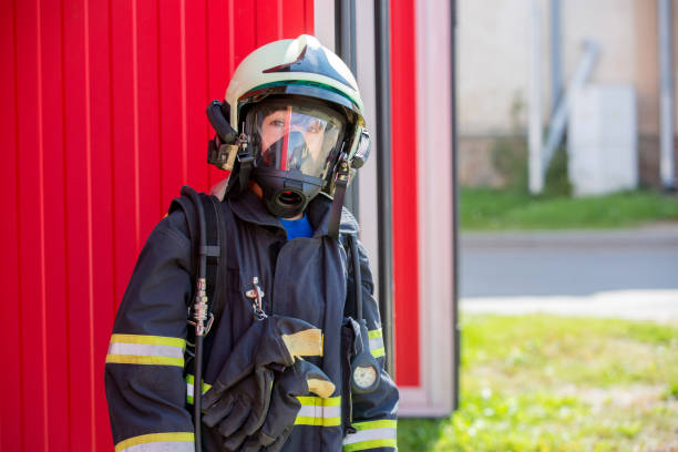 istock Child, cute boy, dressed in fire fighers cloths in a fire station with fire truck 1345336825