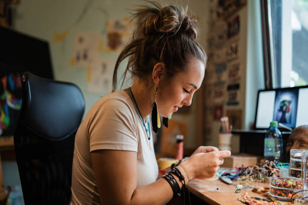 female small business owner, making an hadmade custom jewlery in her home workshop - 人造珠寶 個照片及圖片檔