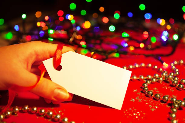 istock A woman's hand holds a white label, on a decorated Christmas background, copy space 1345340822