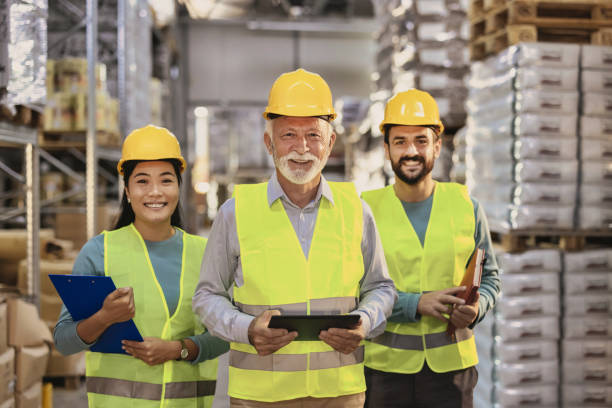 We make success happen Portrait of multiethnic staff at distribution warehouse posing at camera. Aged manager looking at camera with team standing on background in factory storehouse age contrast stock pictures, royalty-free photos & images