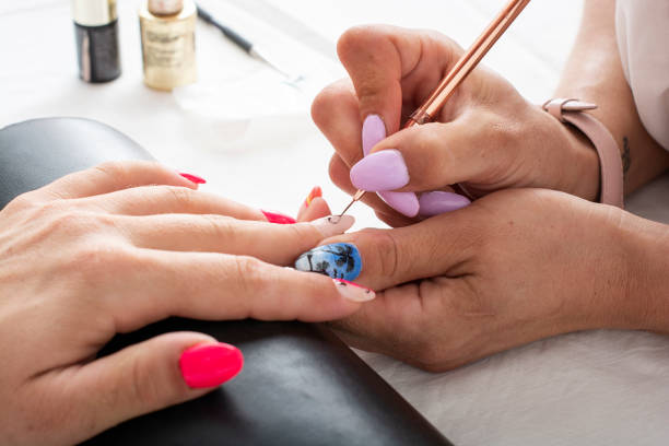 Jeune Femme Recevant Une Manucure à L'aérographe Dans Un Salon De Manucure.  Procédure De Pulvérisation De Peinture Sur Les Ongles