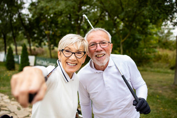 retrato de una pareja de ancianos sonriente en el campo de golf disfrutando viendo el torneo de juego. - retirement golfer happiness relaxation fotografías e imágenes de stock