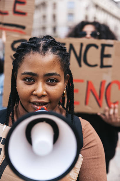 istock Young woman shouting on megaphone during a protest 1345349212