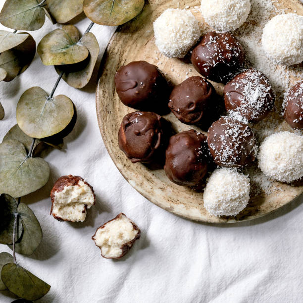istock Raw vegan coconut chocolate candy balls over white with eucalyptus branches. Flat lay 1345350294
