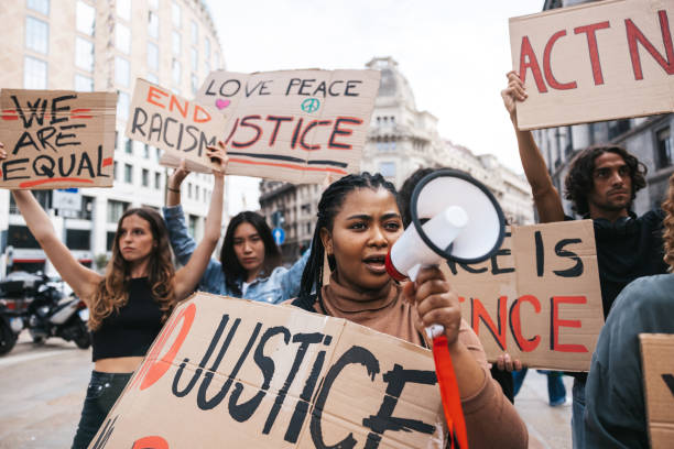 People united against racism. Anti-Racism protest. Protestors holding hand-made signs on cardboards and marching together in the city streets in downtown.