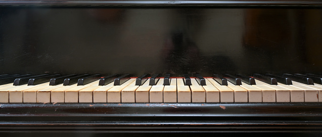 istock Old black grand piano keyboard with keys from ivory and ebony, part of a musical instrument in panoramic format, copy space, selected focus, narrow depth of field 1345354395