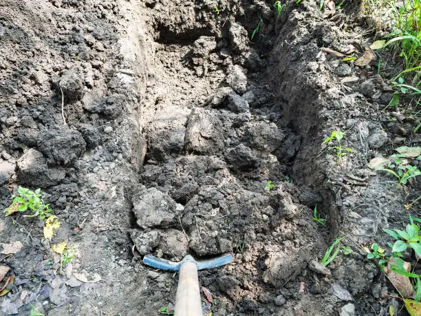 point-of-view shot of digging a trench with bayonet shovel on summer day