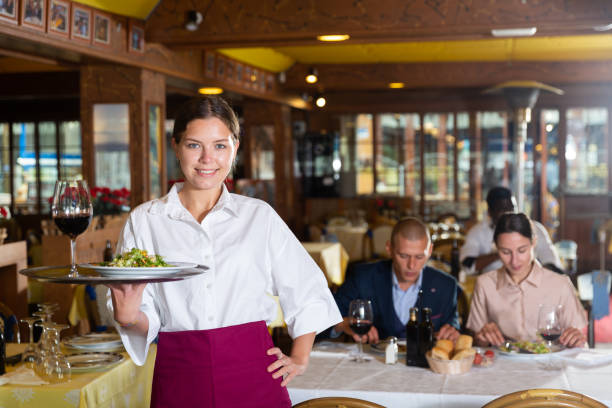 istock Waiter holding tray at restaurant with customers behind him 1345360188