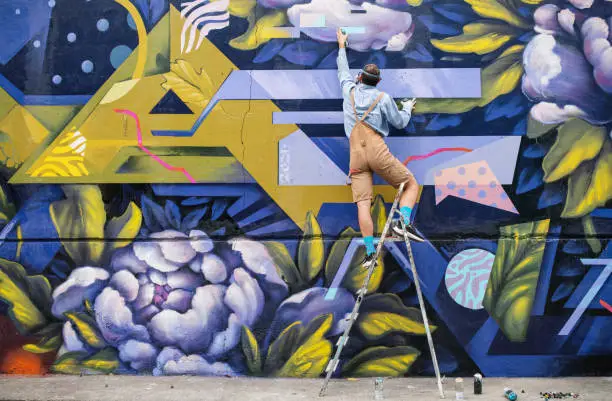 Photo of Street Artist On A Ladder Drawing On Wall