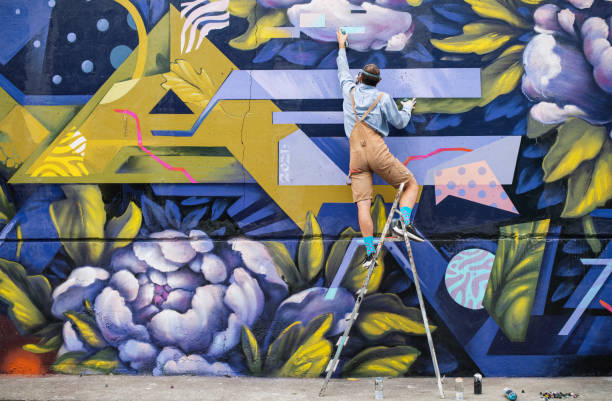 street artist on a ladder drawing on wall - graffiti men wall street art imagens e fotografias de stock