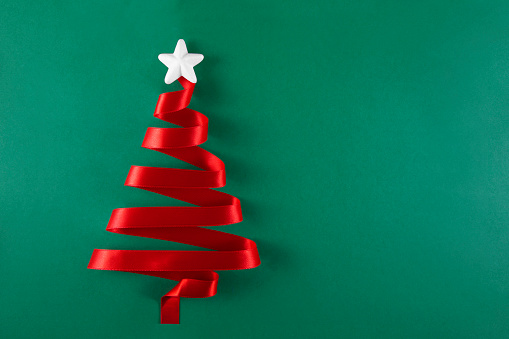 Christmas tree was made of red ribbon on green background