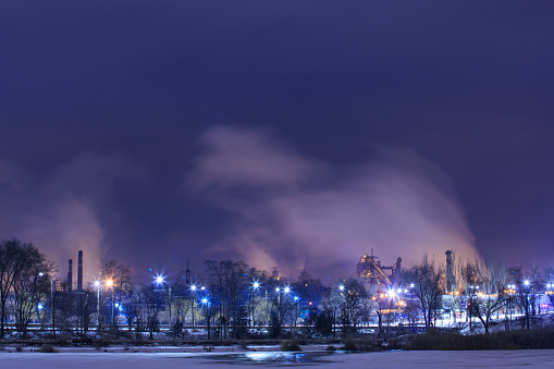 Nighttime winter snow scenery on the blast furnace of the iron and steel works, shot on a slow shutter speed. Metallurgical plant in winter at night