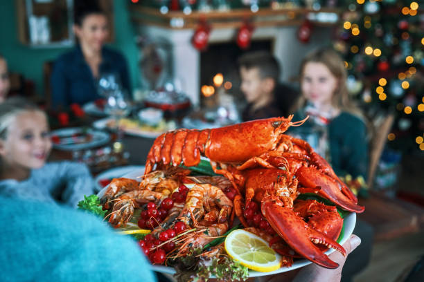 família tendo jantar de natal com filé de peixe de salmão, vieiras, lagosta, camarões e bolo de natal - food dinner prepared fish gourmet - fotografias e filmes do acervo