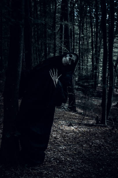 istock Funny pose Grim Reaper in the dark woods. 1345369027