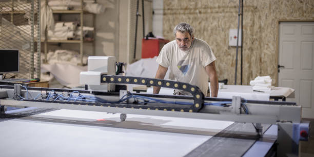 istock Technician works on CNC digital cutter machine for cutting textile 1345370431