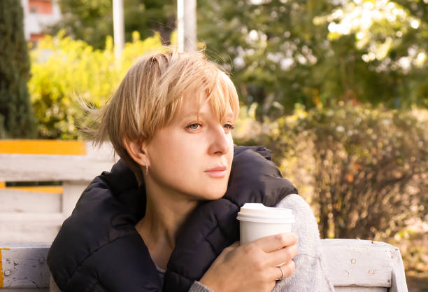 通りの肖像画のカフェでコーヒーを飲むペンシブな女性 - senior adult loneliness one person sadness ストックフォトと画像