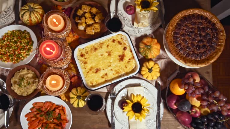 Table is set up for Thanksgiving celebration. On the table is a traditional stuffed roasted turkey with side dishes and pecan pie