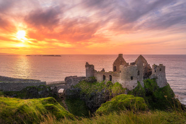 Dunluce Castle on the cliff in Bushmills, sunset Bushmills, Antrim, Northern Ireland, Aug 2019 Sunset at ruins of Dunluce Castle located on the edge of cliff, Bushmills, Northern Ireland. Filming location of popular TV show Game of Thrones headland photos stock pictures, royalty-free photos & images
