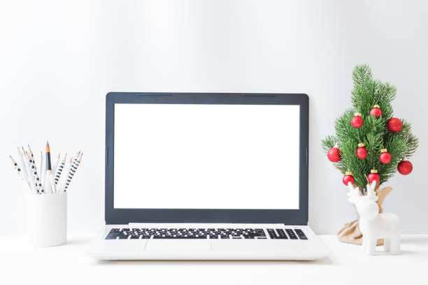 istock Office workspace with laptop mockup screen, christmas tree, deer, supplies on a light background. Christmas home interior or office background 1345371743